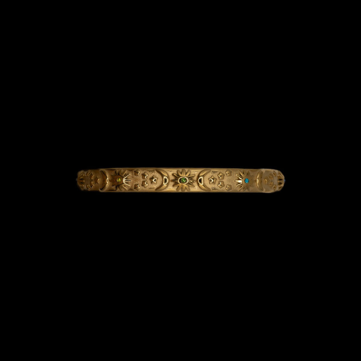 Gold bracelet on celestial theme sun moon stars with multicolored gemstones on a black background