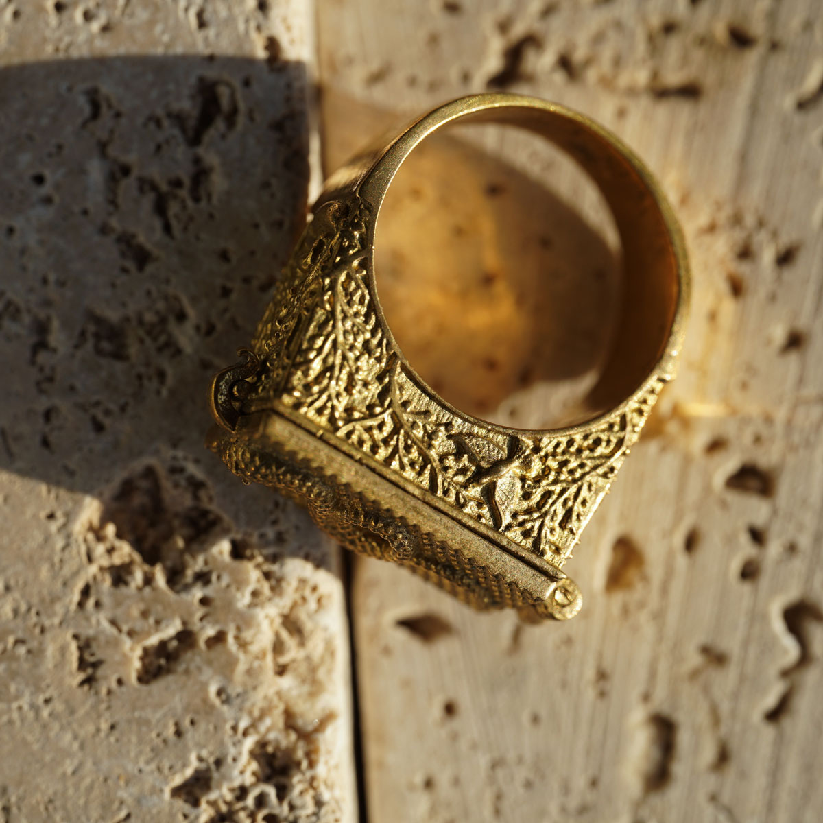 Side view of golden antique brass poison ring with intricate snake design