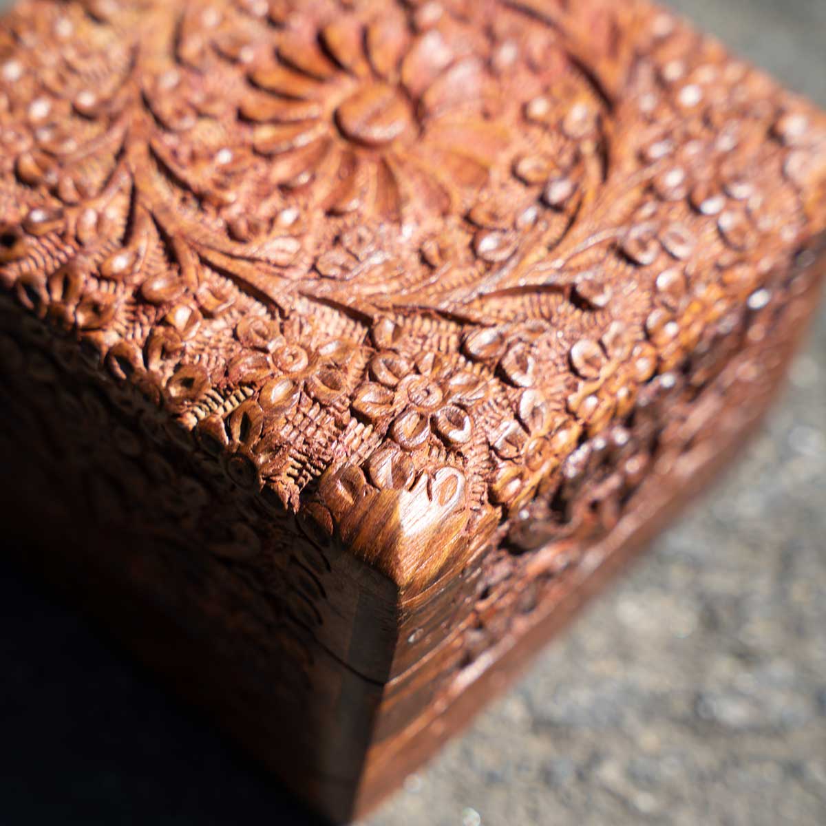 Close up view of a Decorative wooden kashmiri jewellery box with intricate carvings on a textured surface