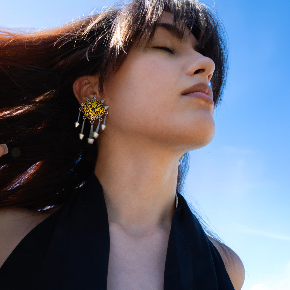 Woman wearing a large, ornate indian earring with hand-painted meenakari enamel pattern