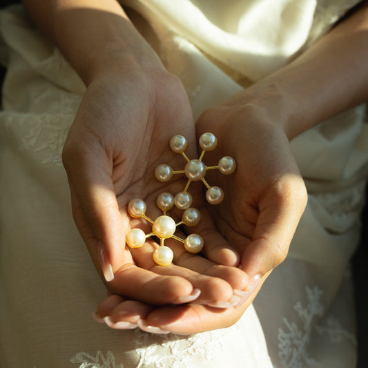 Woman holding an earring with decorative geometric arrangement of pearls