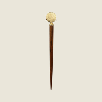 Decorative circle shaped handmade wooden and brass hairpin stick with brass tip on a beige background