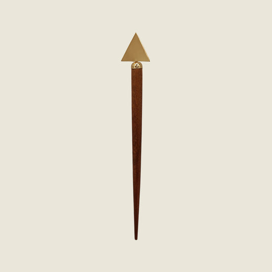 Decorative triangle shaped handmade wooden and brass hairpin stick with brass tip on a beige background
