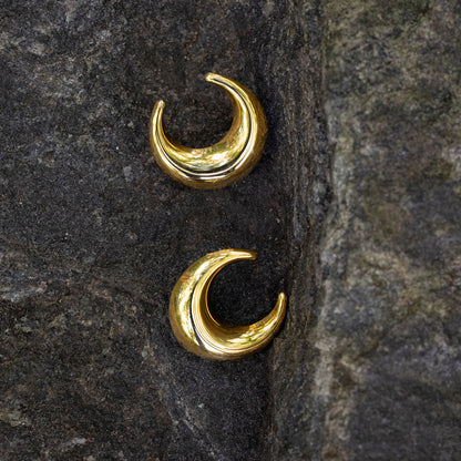 Gold crescent moon earrings on a dark stone surface