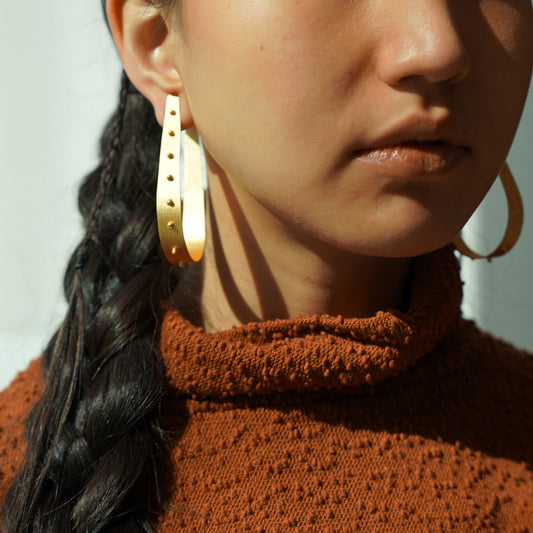 Woman wearing gothic golden hoop earrings