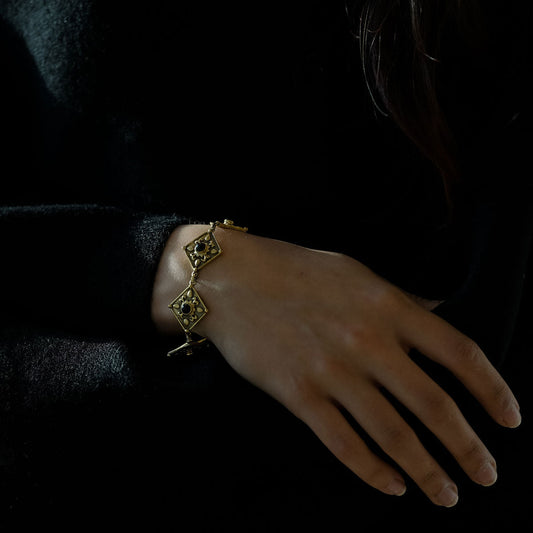 Woman wearing antique golden brass bracelet with black onyx medieval style