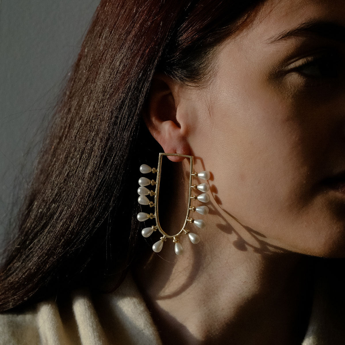 Woman wearing u-shaped pearl earrings