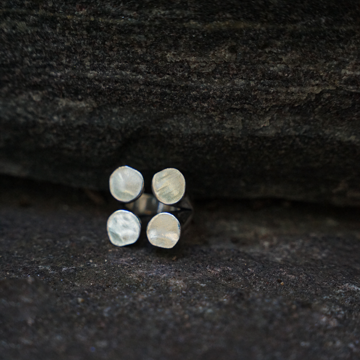 A silver-plated ring with four matte finished circles arranged in a geometric pattern