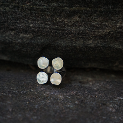 A silver-plated ring with four matte finished circles arranged in a geometric pattern