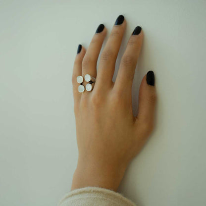 A silver-plated ring with four matte finished circles arranged in a geometric pattern