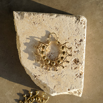 Lightweight intricate designed earrings in a circular geometric pattern kept on stone surface