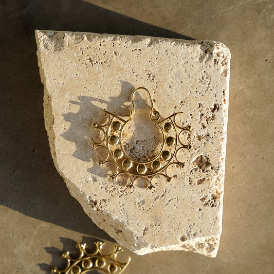 Lightweight intricate designed earrings in a circular geometric pattern kept on stone surface