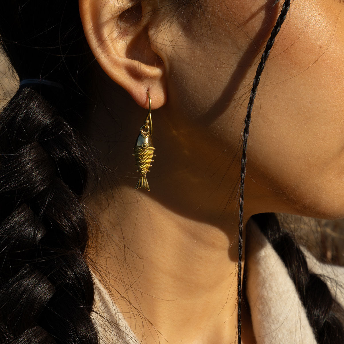 Woman wearing a golden fish shape earring