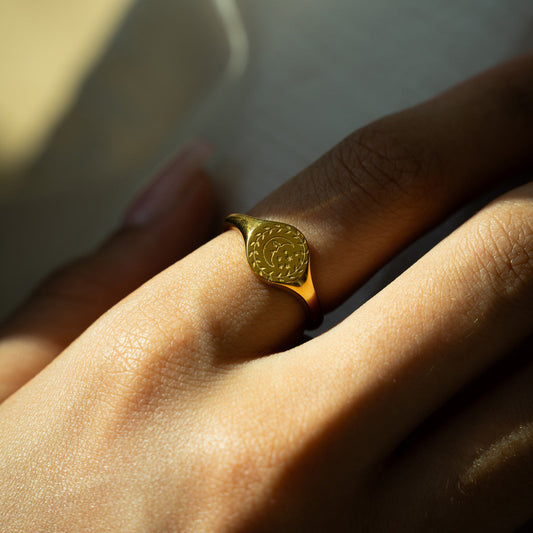 Golden signet ring with a crescent moon engraving on a woman's finger