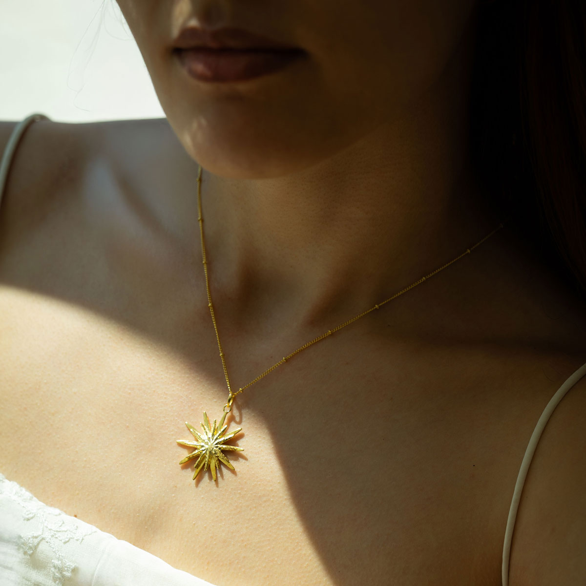 Close-up of a person wearing a golden necklace with a star-shaped pendant