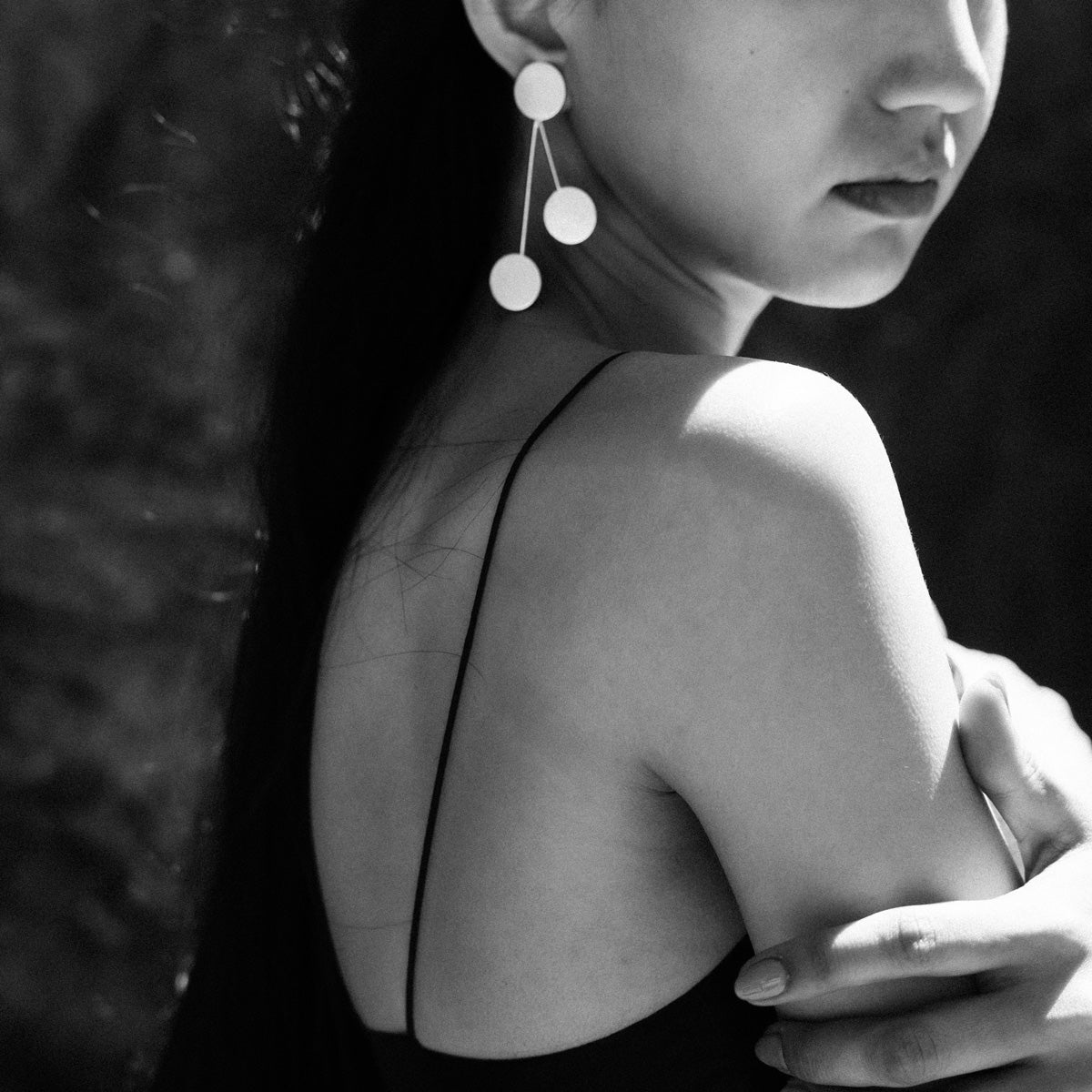 Woman wearing a golden brass earring with three geometric circles