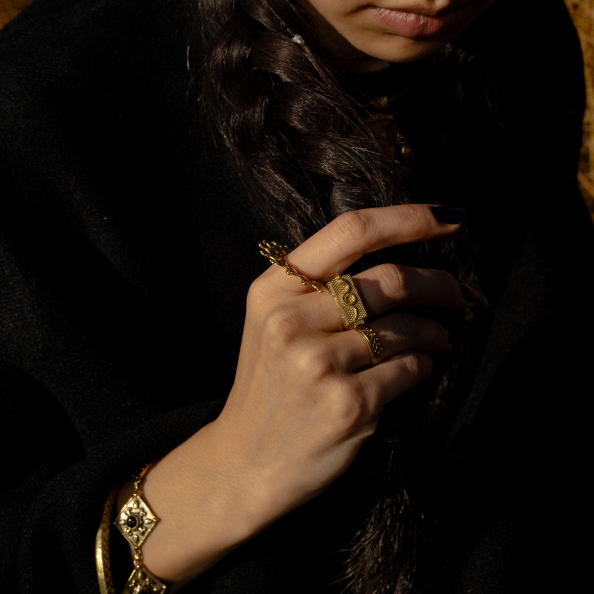 Close-up of a woman wearing golden eclectic boho jewelry with a dark background