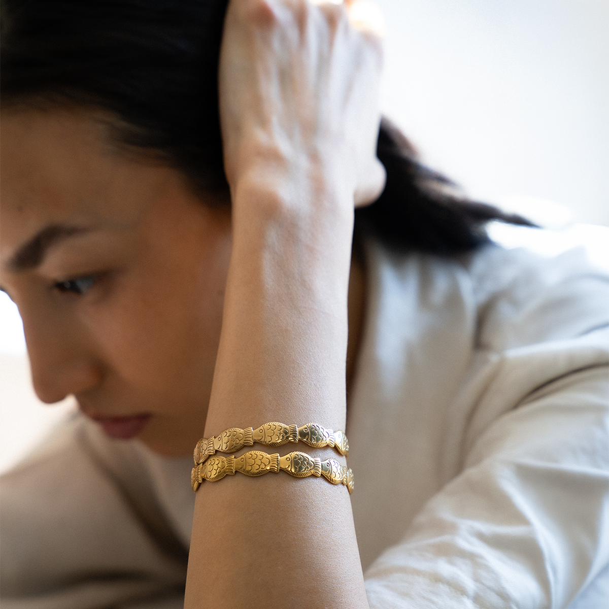 Woman wearing a gold plated fish shaped bracelet set