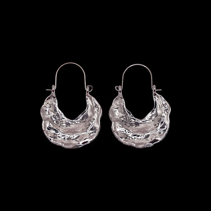 Pair of silver textured hoop earrings on a black background