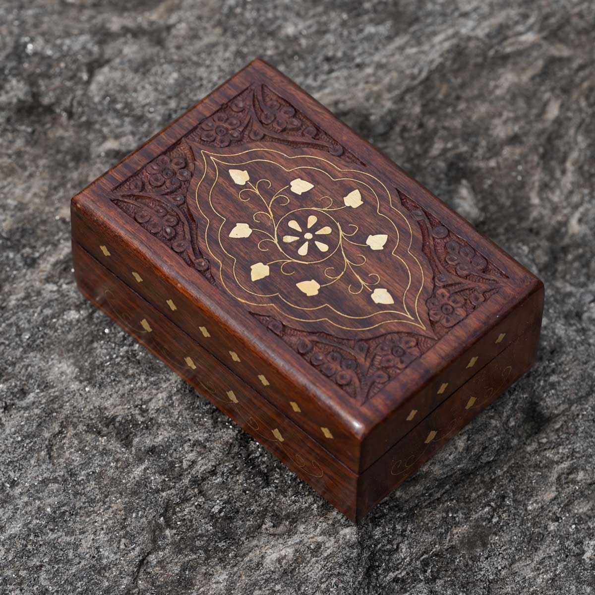 Decorative wooden gift, hand-carved, box with golden brass etchings on a stone
