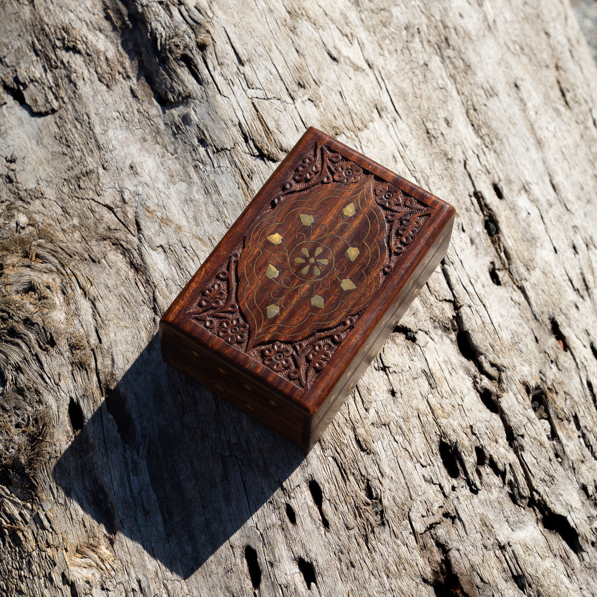Decorative wooden gift, hand-carved, box with golden brass etchings on a stone