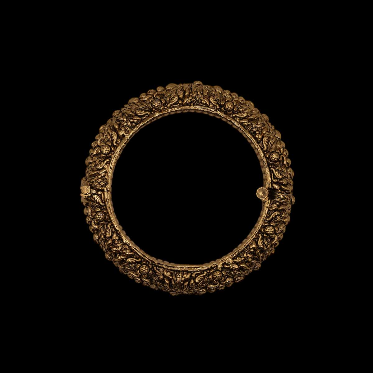 Antique ornate brass indian golden bracelet with intricate engravings on a black background