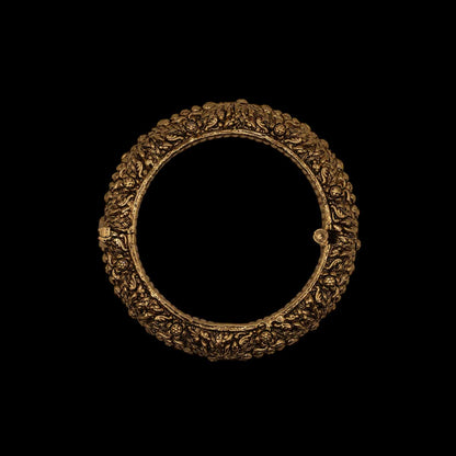Antique ornate brass indian golden bracelet with intricate engravings on a black background