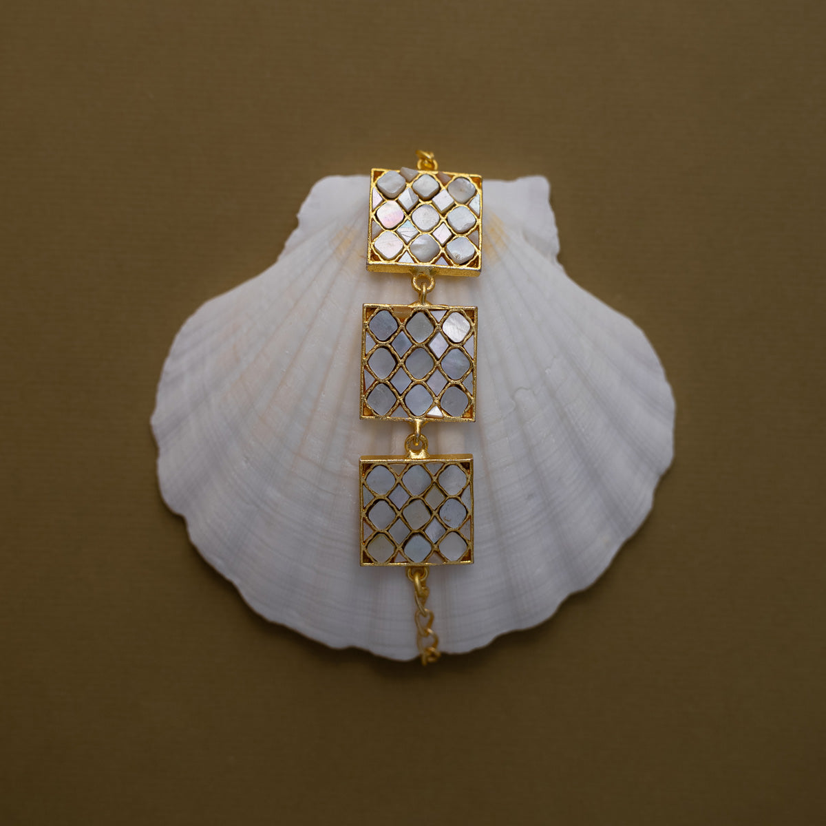 Golden bracelet with mother of pearls arranged in a square shaped bracalet