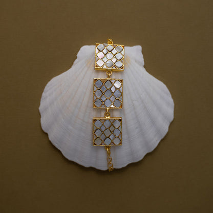 Golden bracelet with mother of pearls arranged in a square shaped bracalet