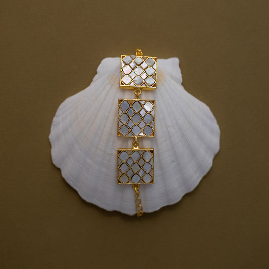Golden bracelet with mother of pearls arranged in a square shaped bracalet