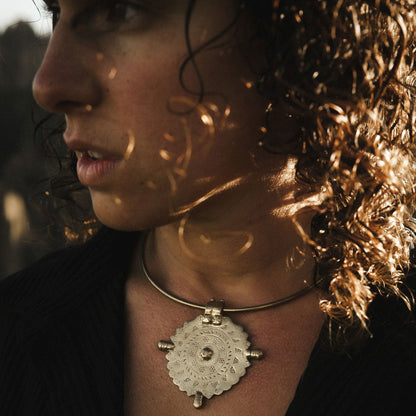Close-up of a model wearing a bohemian necklace hasli style with a medallion sun pendant