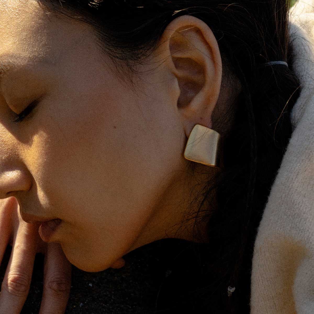 Woman wearing a stainless steel gold-plated curved matte finish earrings