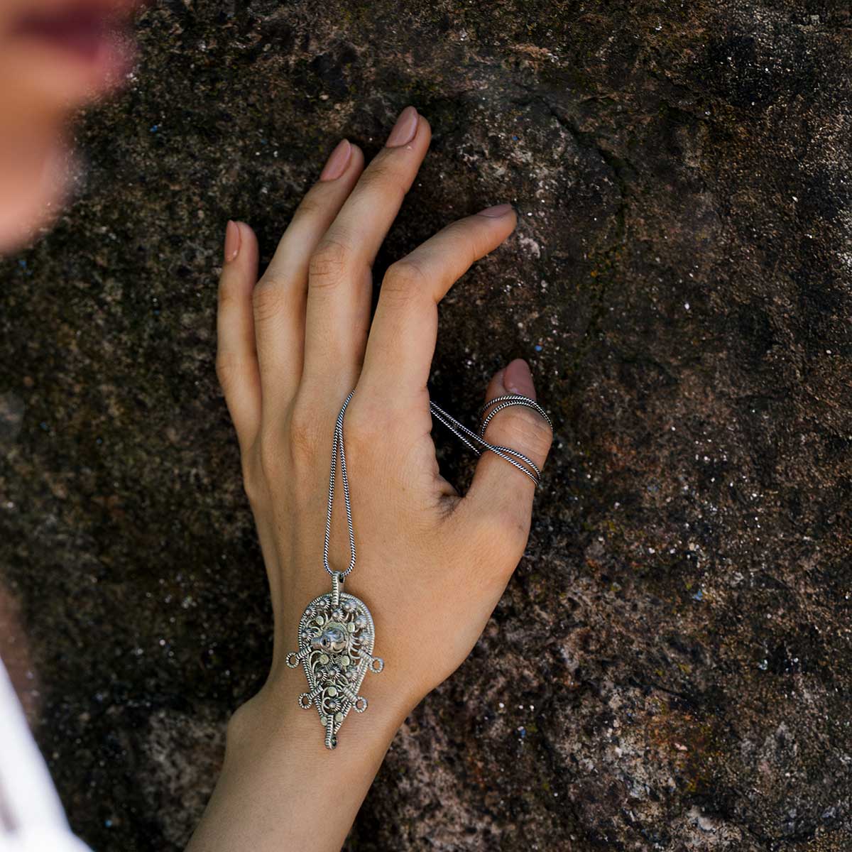 Close-up of a woman holding an intricate afghani german silver pendant 