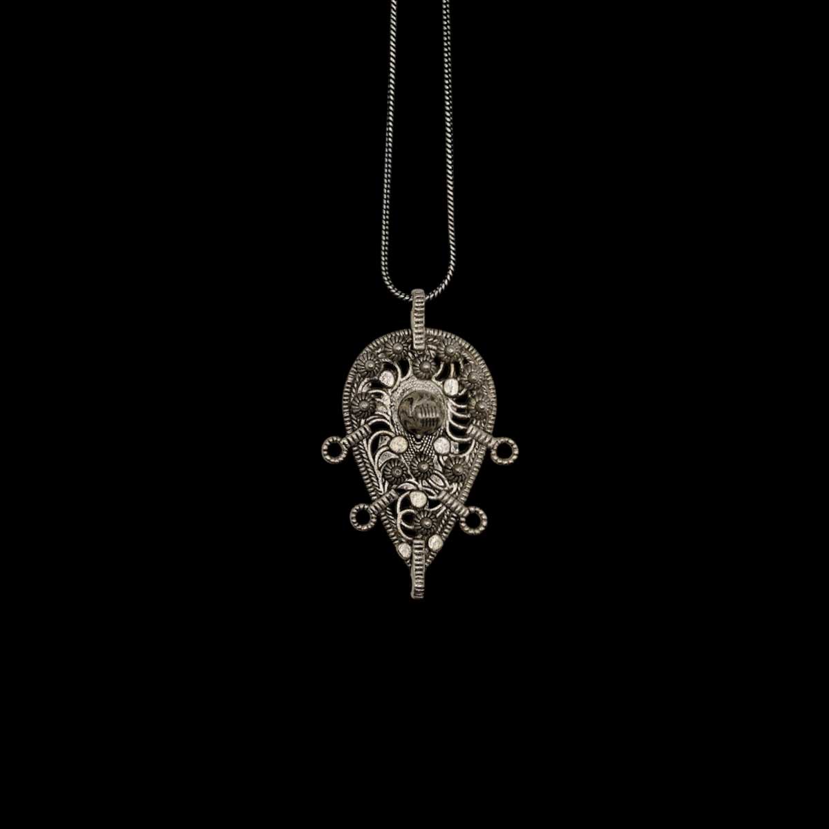 An intricate afghani pendant on a black background