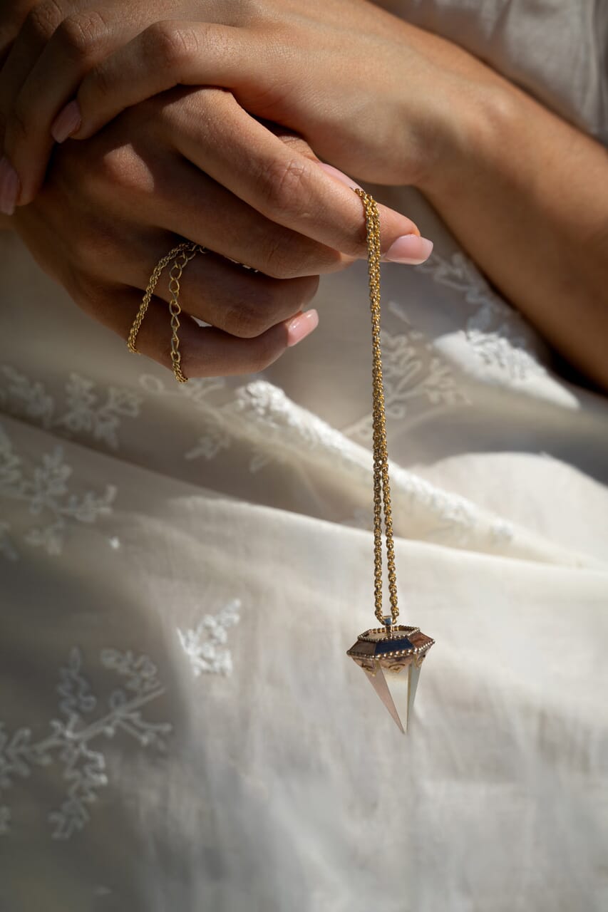 Close-up of a hand holding a crystal pendulum pendant